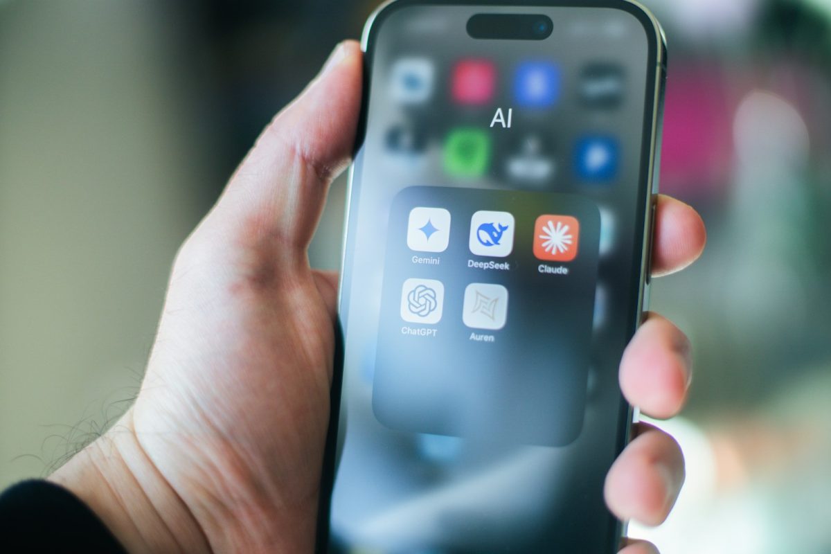 Hand som håller en smartphone med en mapp av AI-appar, bland annat Gemini och ChatGPT