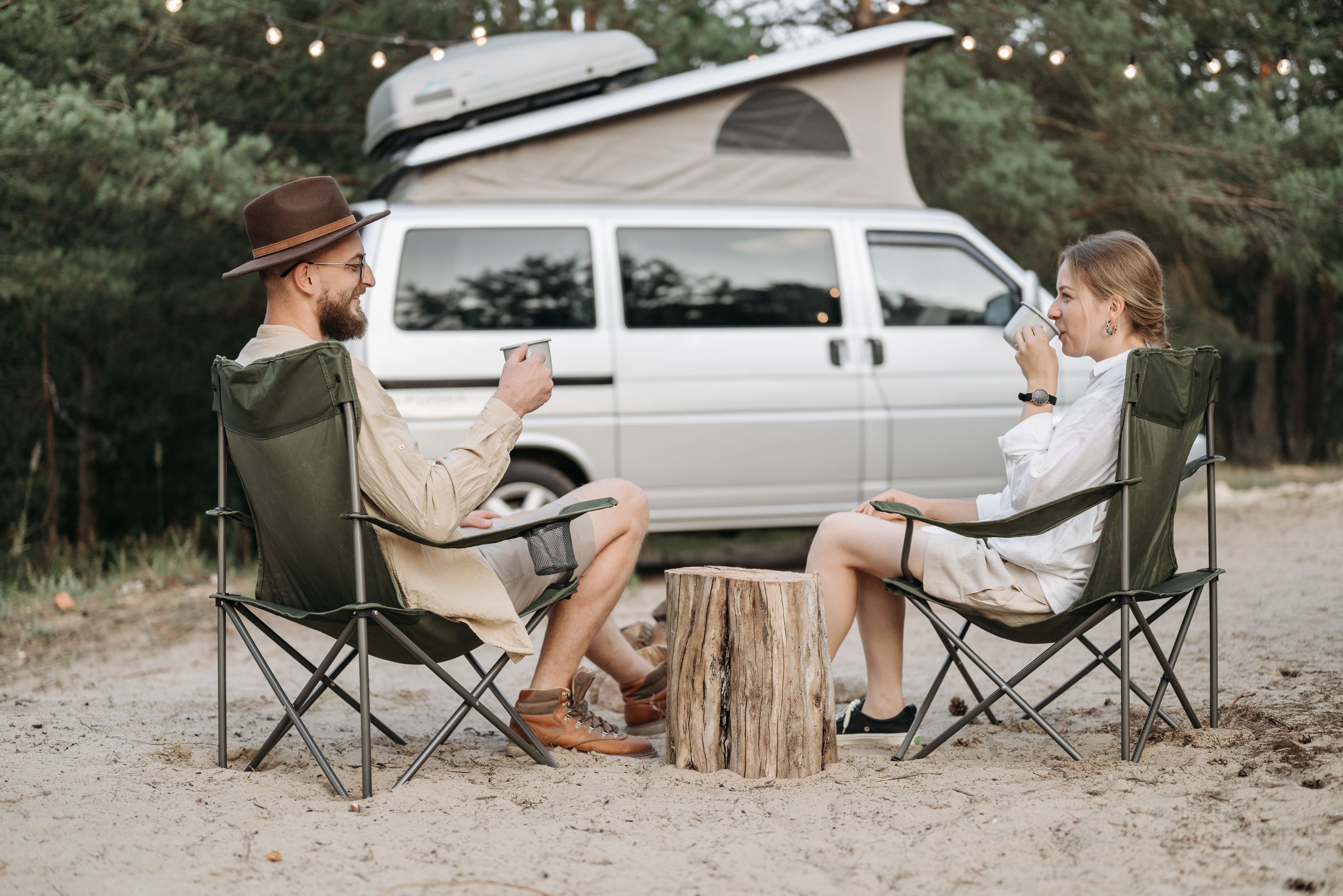 Par som fikar i campingstolar framför en campervan