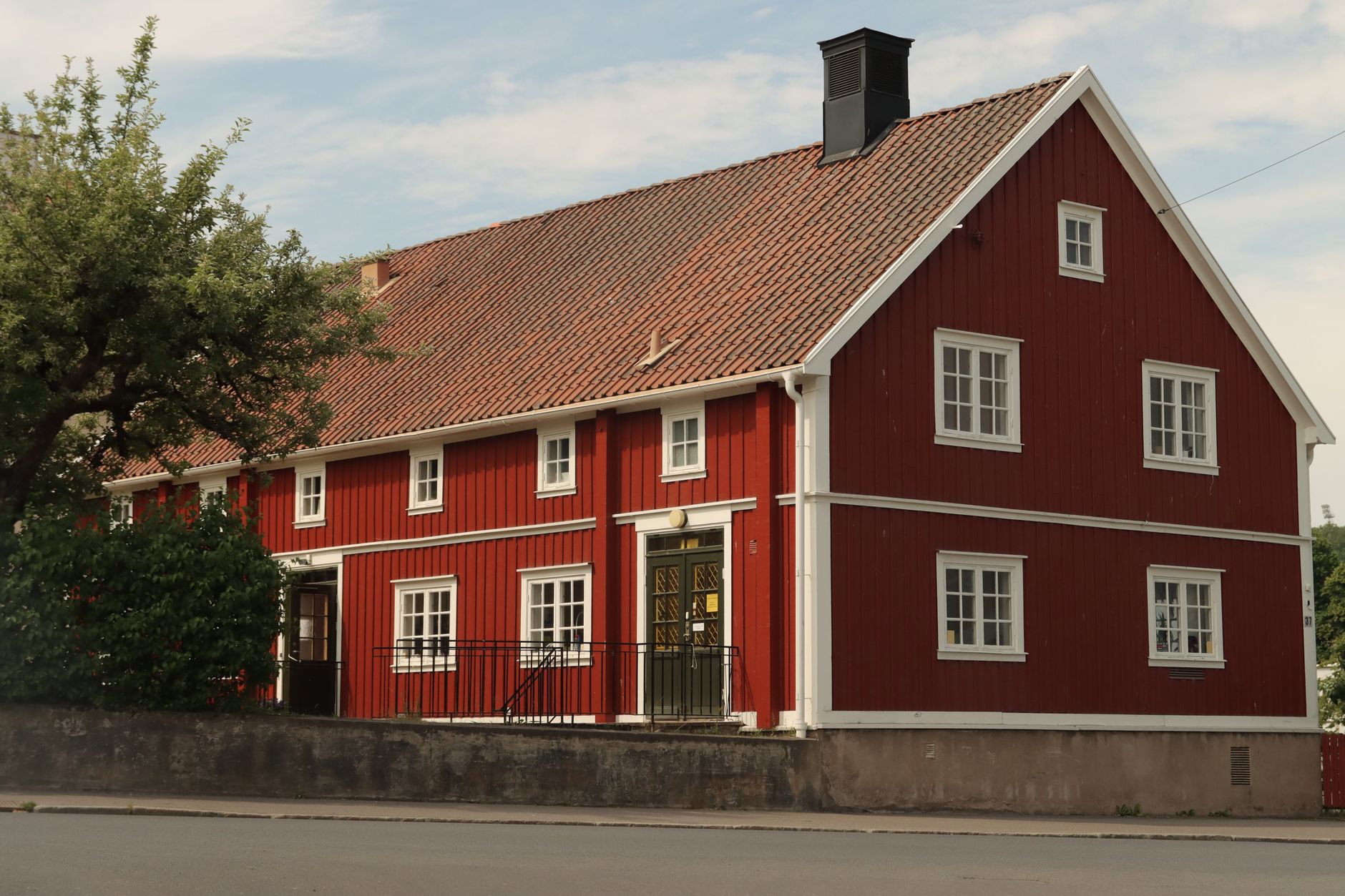 Rött trähus i två våningar med vita fönster och tegeltak