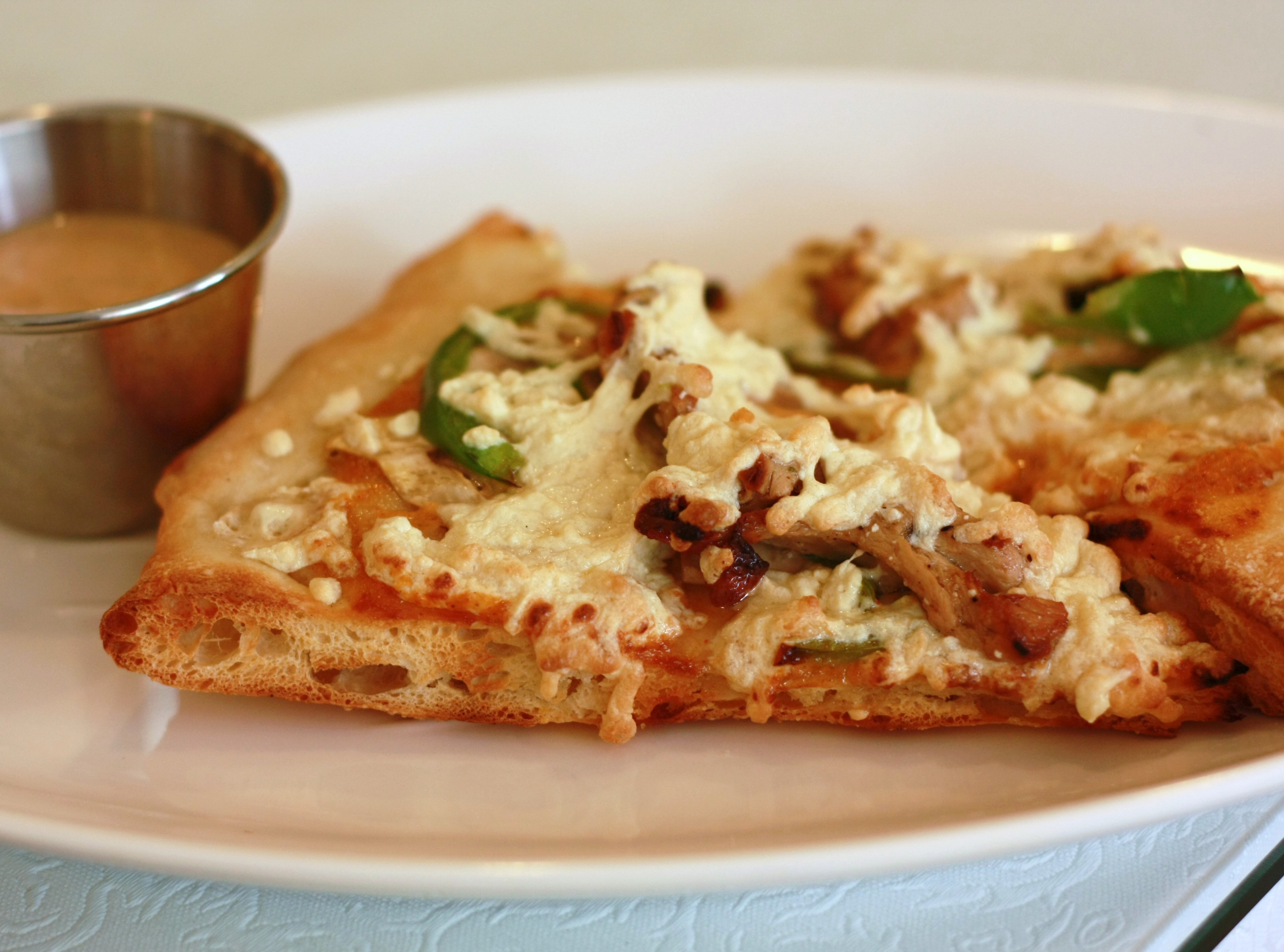 Vegansk pizza med smält, kräm vit ost av märket Daiya, gott om bubblig, gyllenbrun smältyta mellan grönsaker