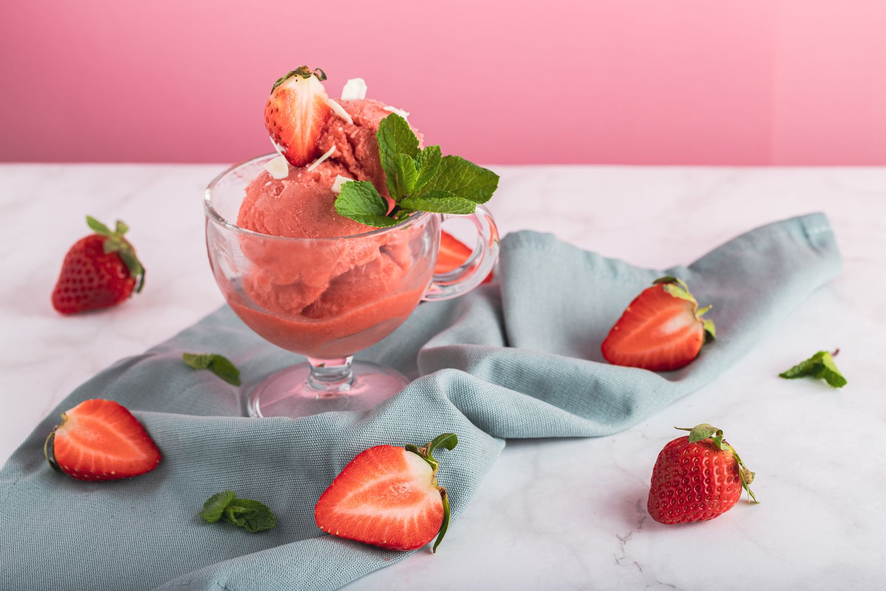 Skopa rosa jordgubbsglass i ett glas, garnerad med färsk mynta och jordgubbar