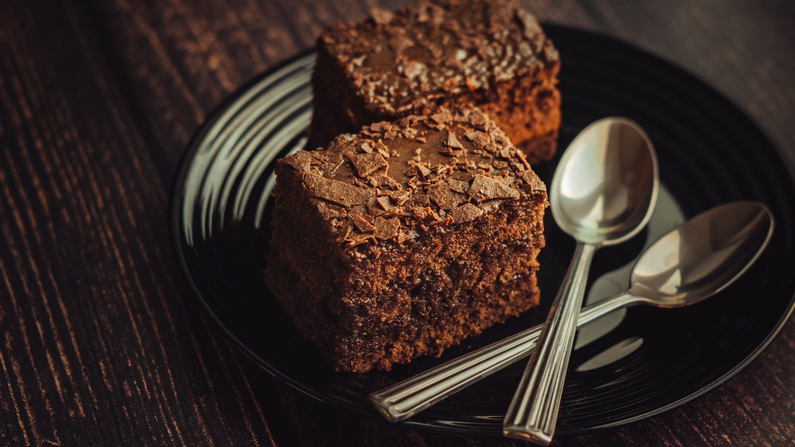 Bitar av vegansk kladdkaka med blank, sprucken yta och kladdig, seg mitt