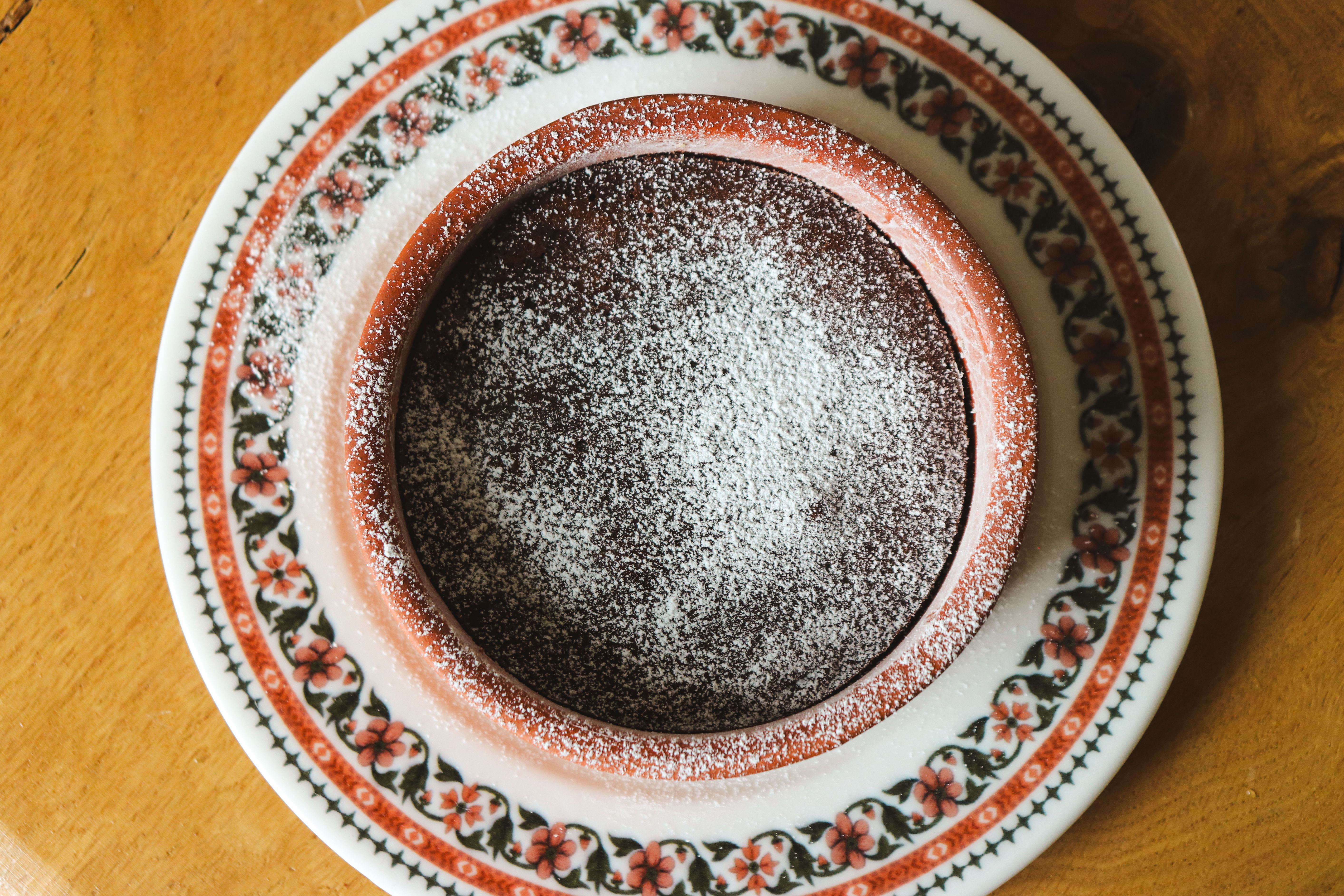 Rund chokladkaka gräddad i form, pudrad med florsocker, sedd uppifrån