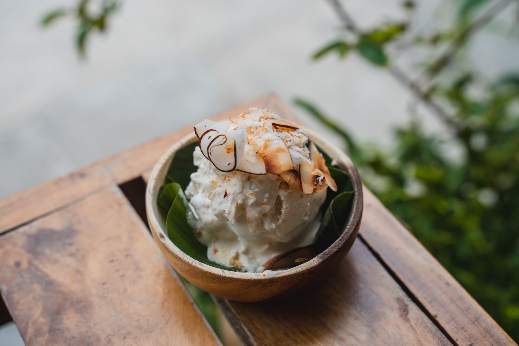 Skopa krämig kokosbaserad vegansk glass i en trakskal, toppad med rostad kokosflarn