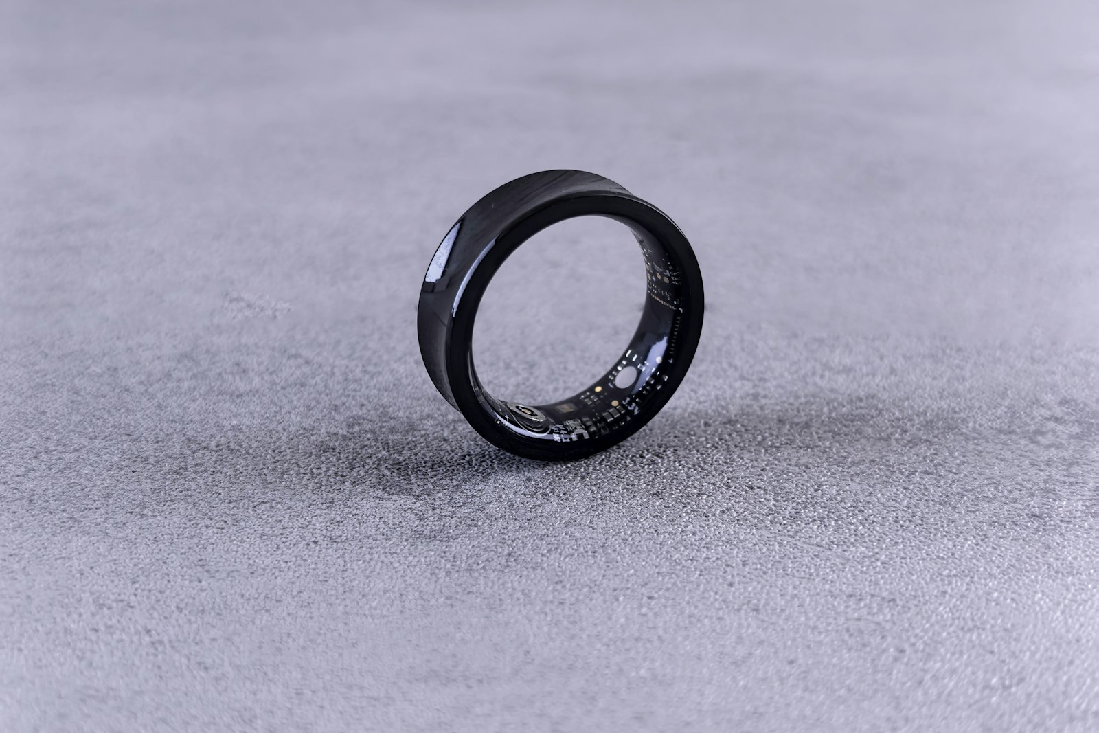 Black smart ring resting on a grey surface