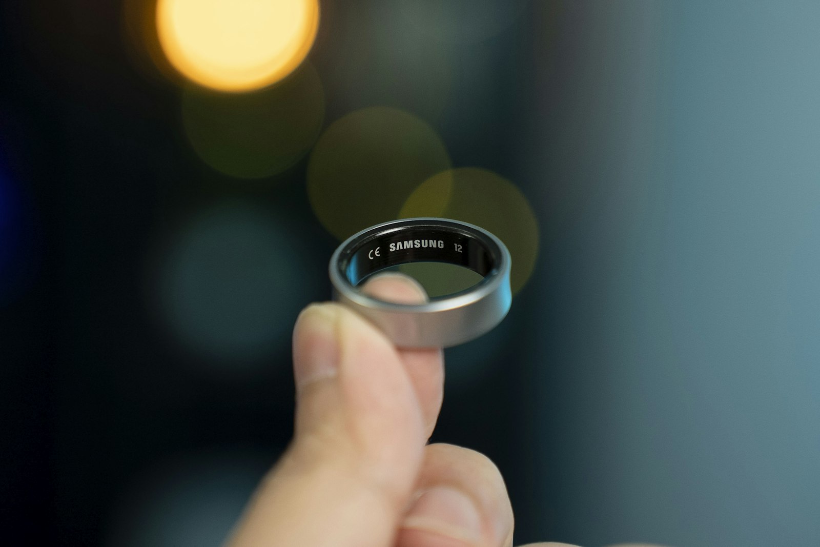 Samsung Galaxy Ring held between fingertips with the model engraving visible