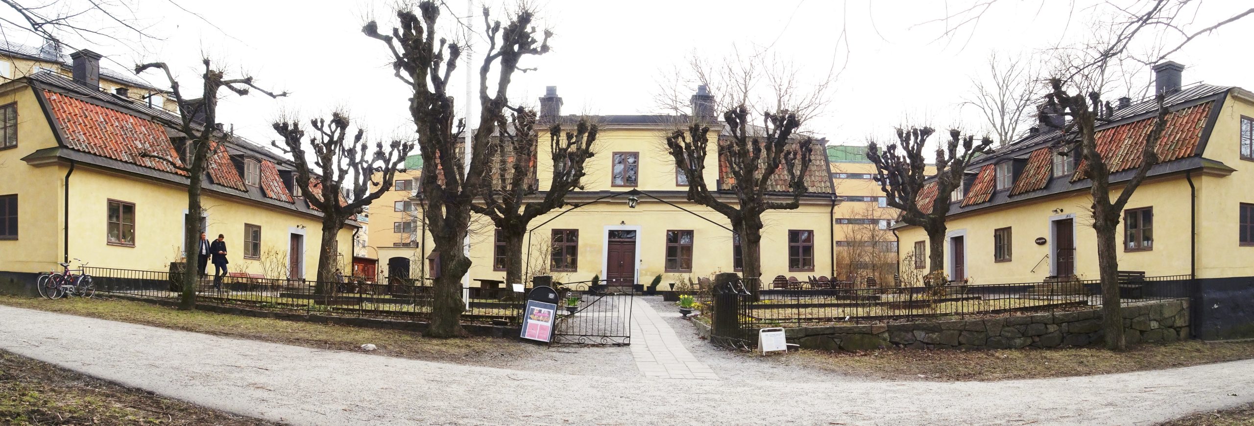 Kristinehovs malmgård vid Hornstull, tre gula putsade hus kring en grusad gårdsplan med hamlade träd.