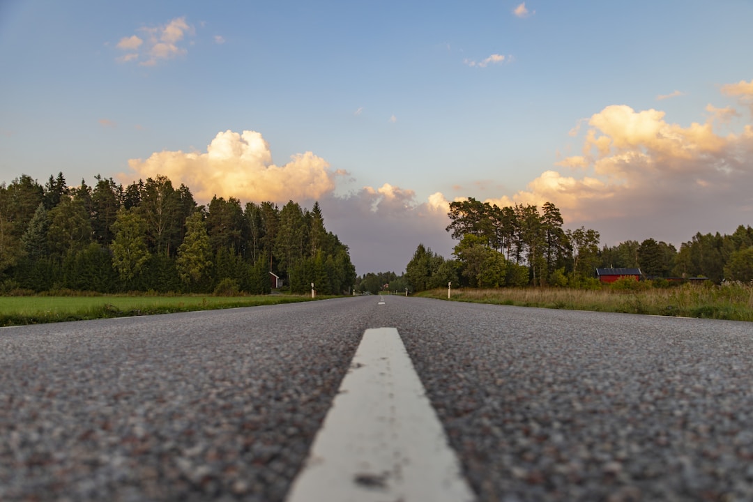 Empty rural road in Sweden with forest and a red house