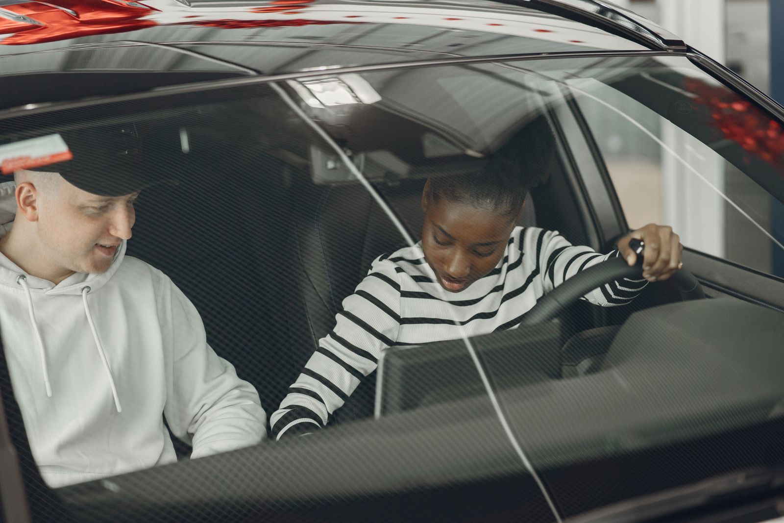 Instructor in the passenger seat explaining to a learner driver holding the steering wheel