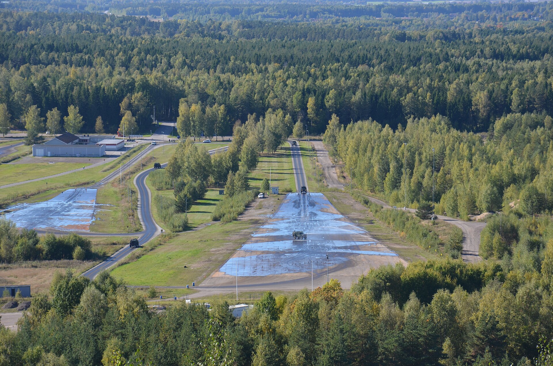 Aerial view of a Swedish skid pan with wet asphalt surfaces surrounded by forest