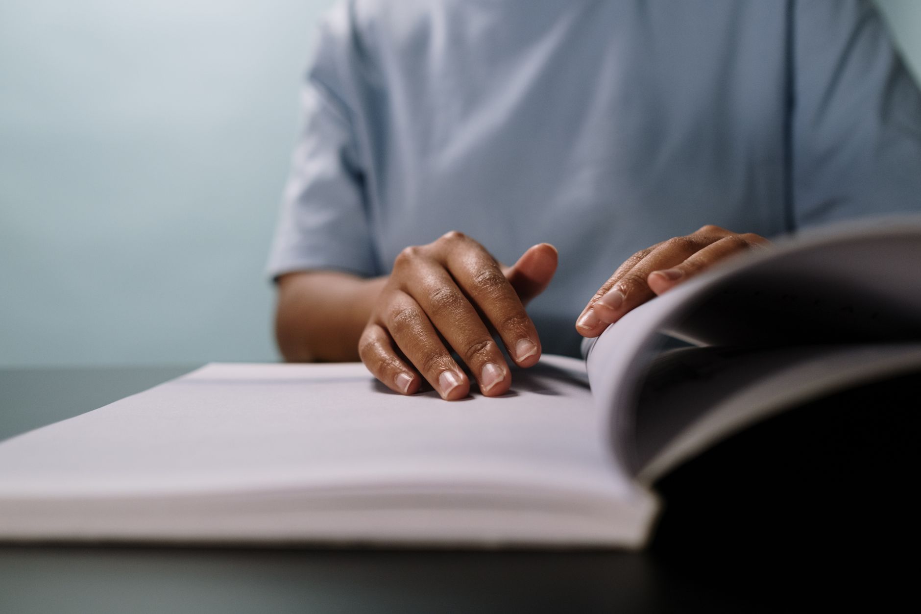 Hands turning the pages of a large open book on a table