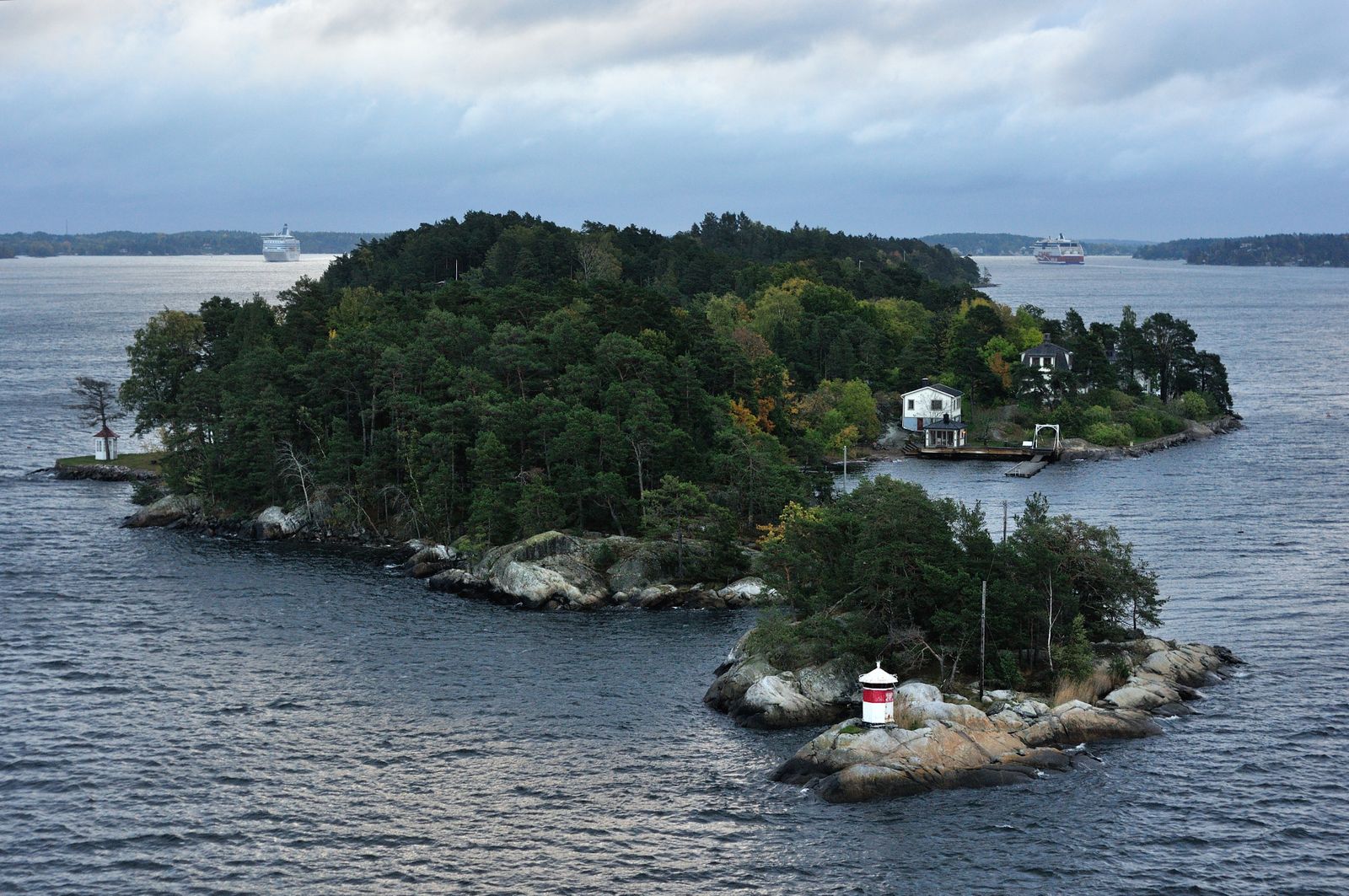 Flygbild över en skogklädd ö med hus i Stockholms skärgård