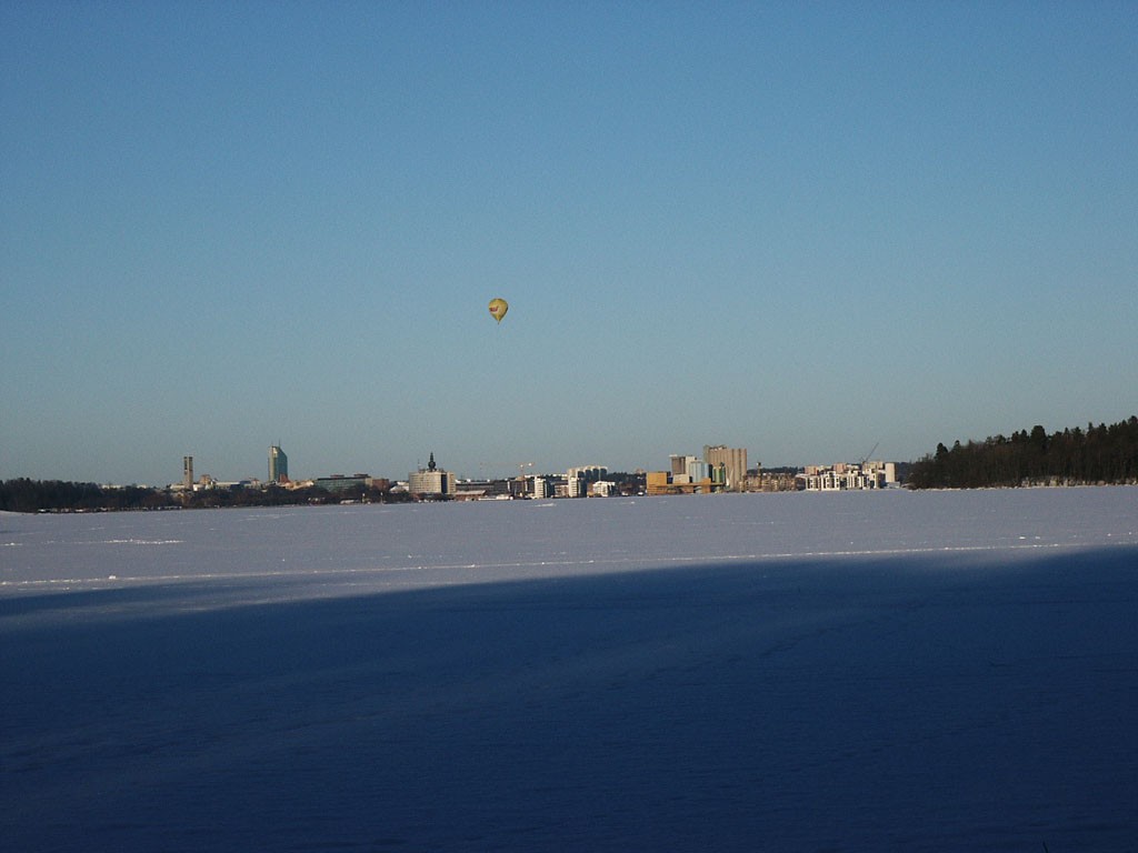 Västerås skyline sett över den frusna Mälaren, med en luftballong i bakgrunden