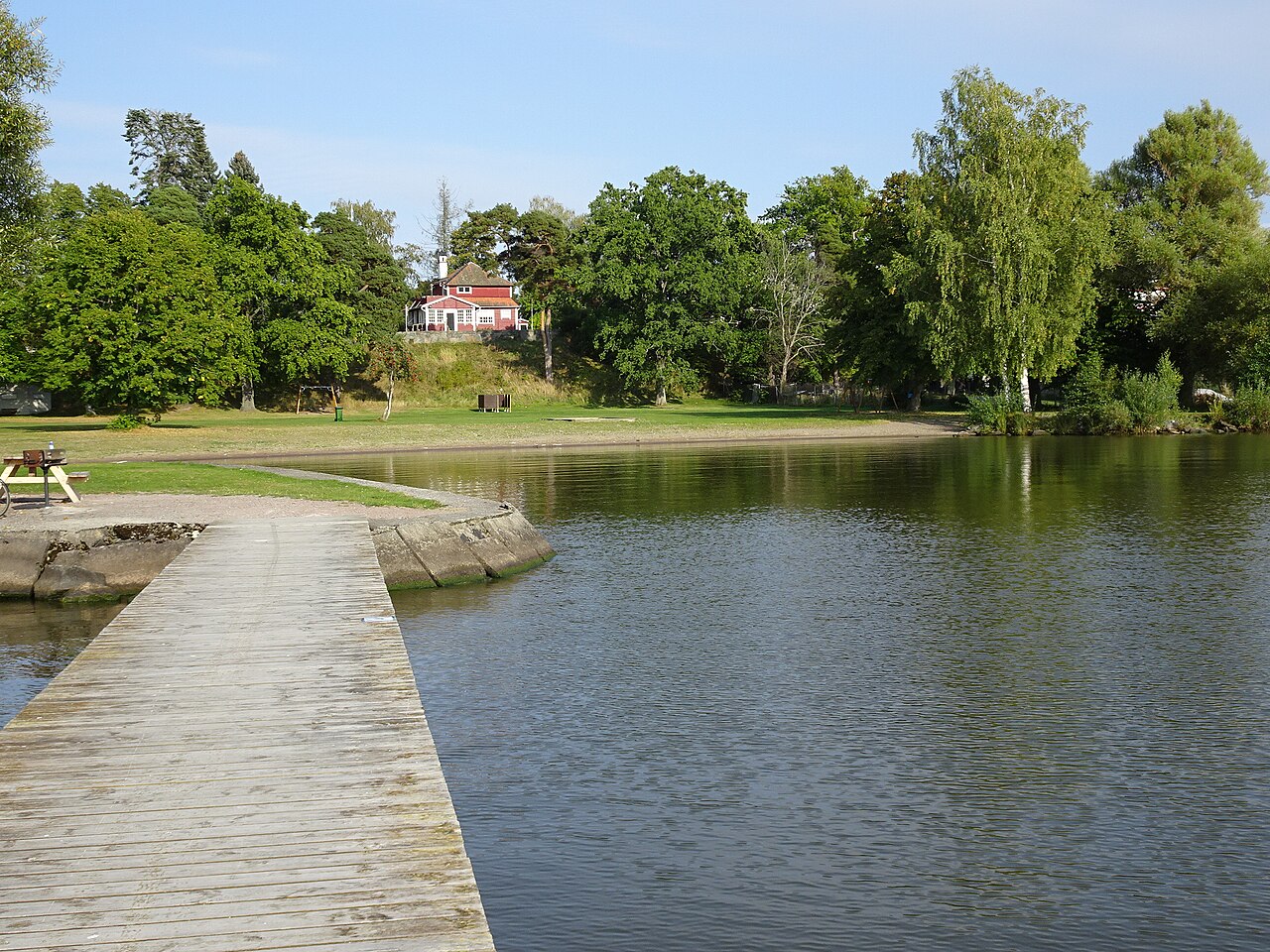 Bryggan och sandstranden vid Framnäs badplats i Västerås, med Mälaren i förgrunden.