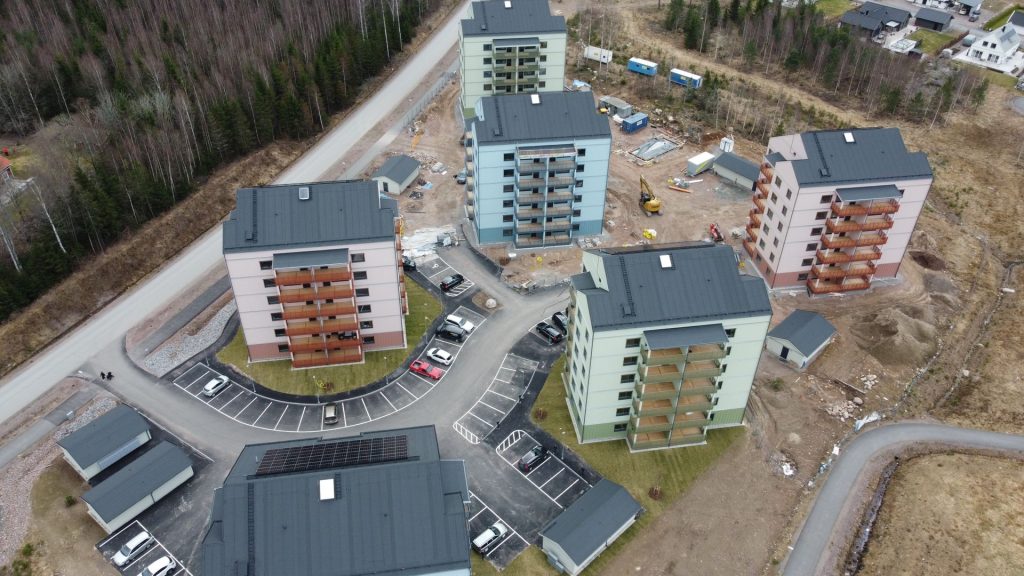 Flygbild över nybyggda flerbostadshus med en pågående byggarbetsplats intill