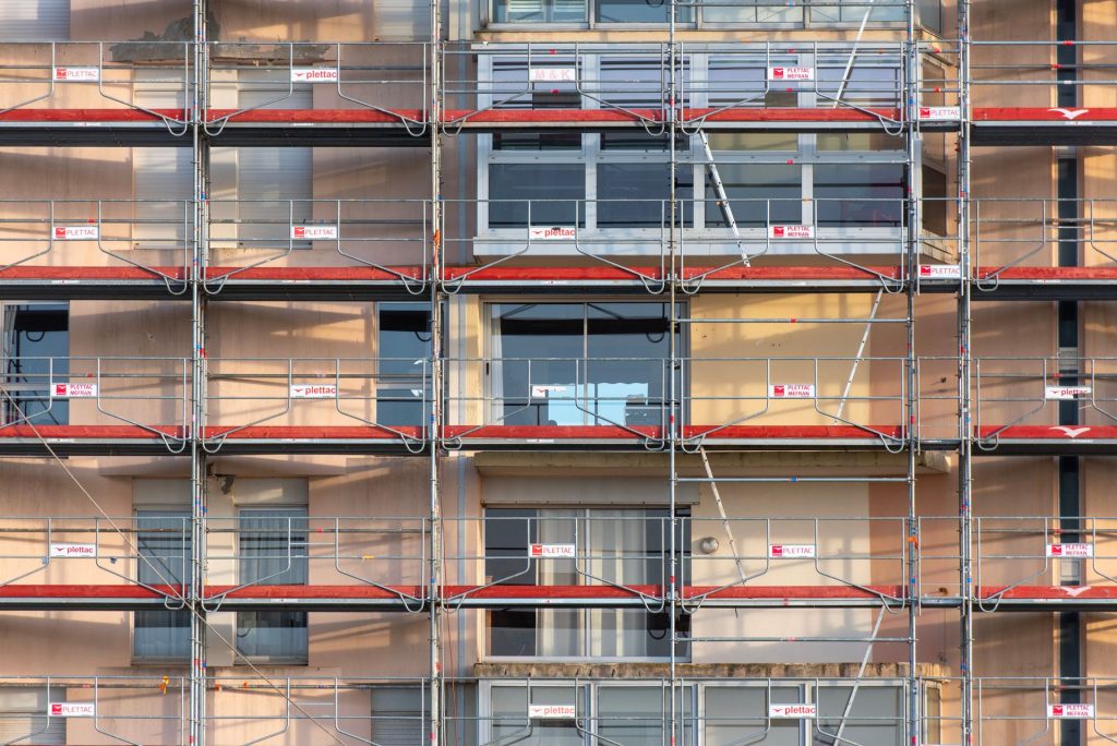 Byggnadsställningar täcker fasaden på ett flerbostadshus under renovering