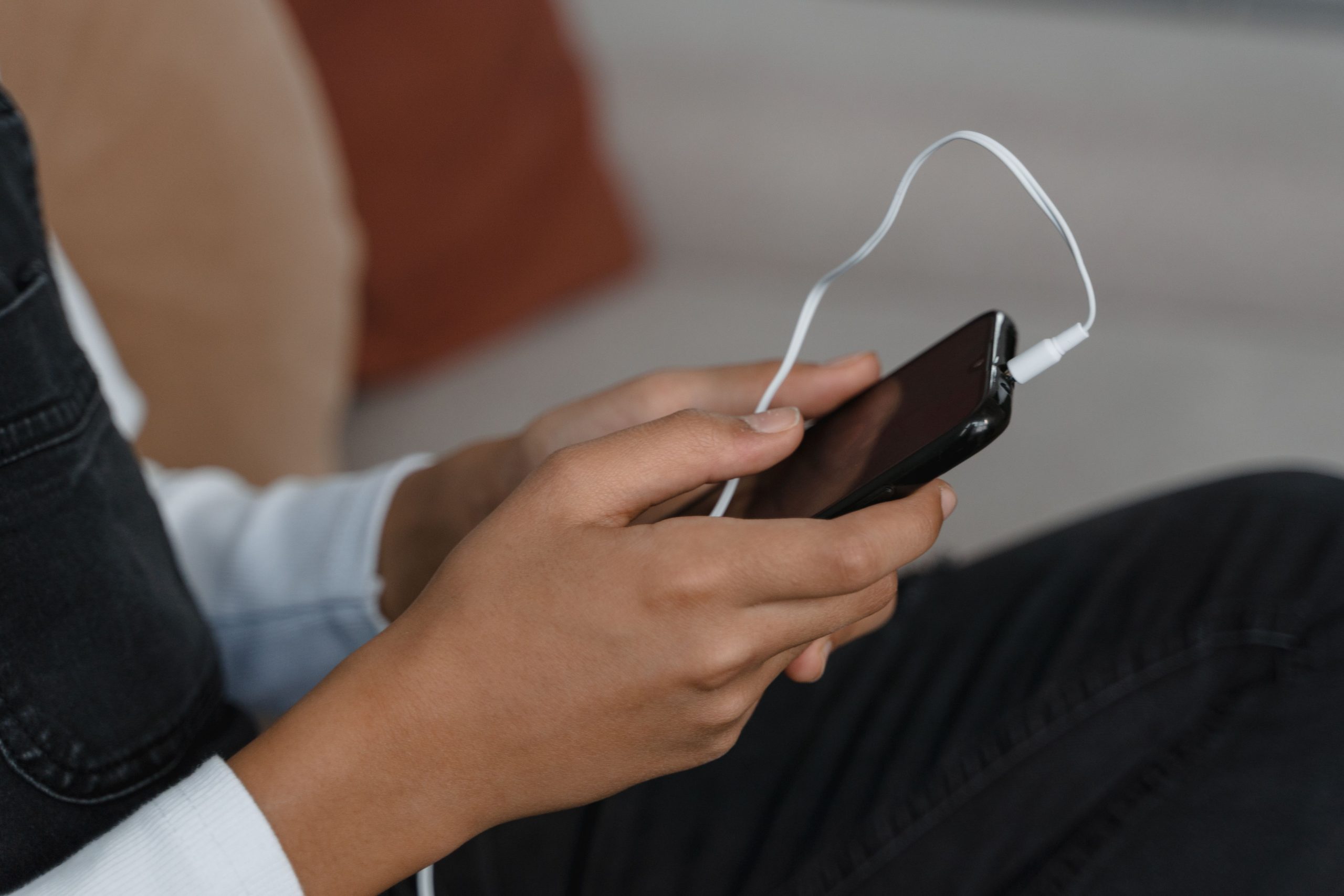 Hander som haller en smartphone med horlurar