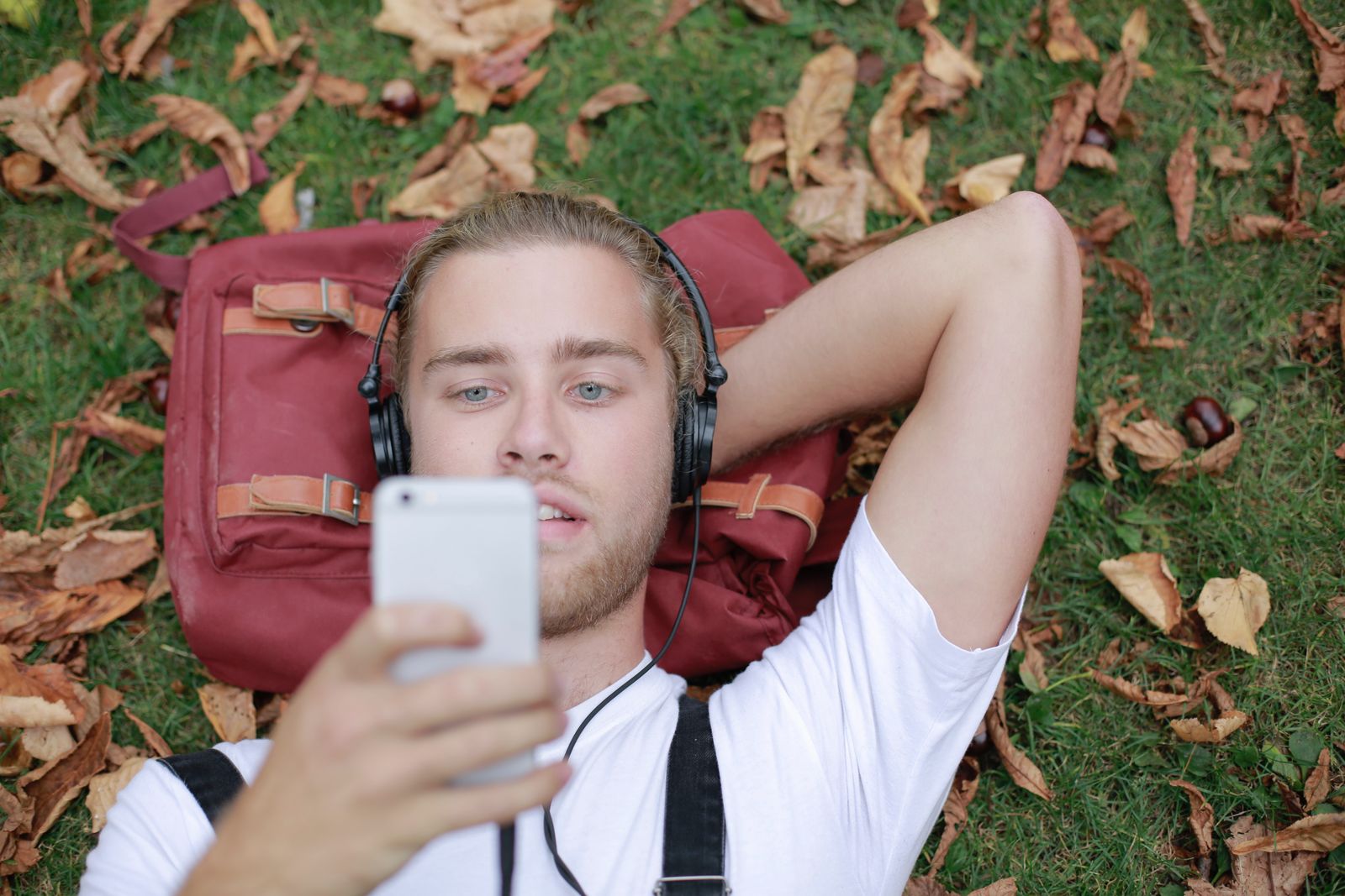 Person som lyssnar på ljudbok i hörlurar med mobilen i handen