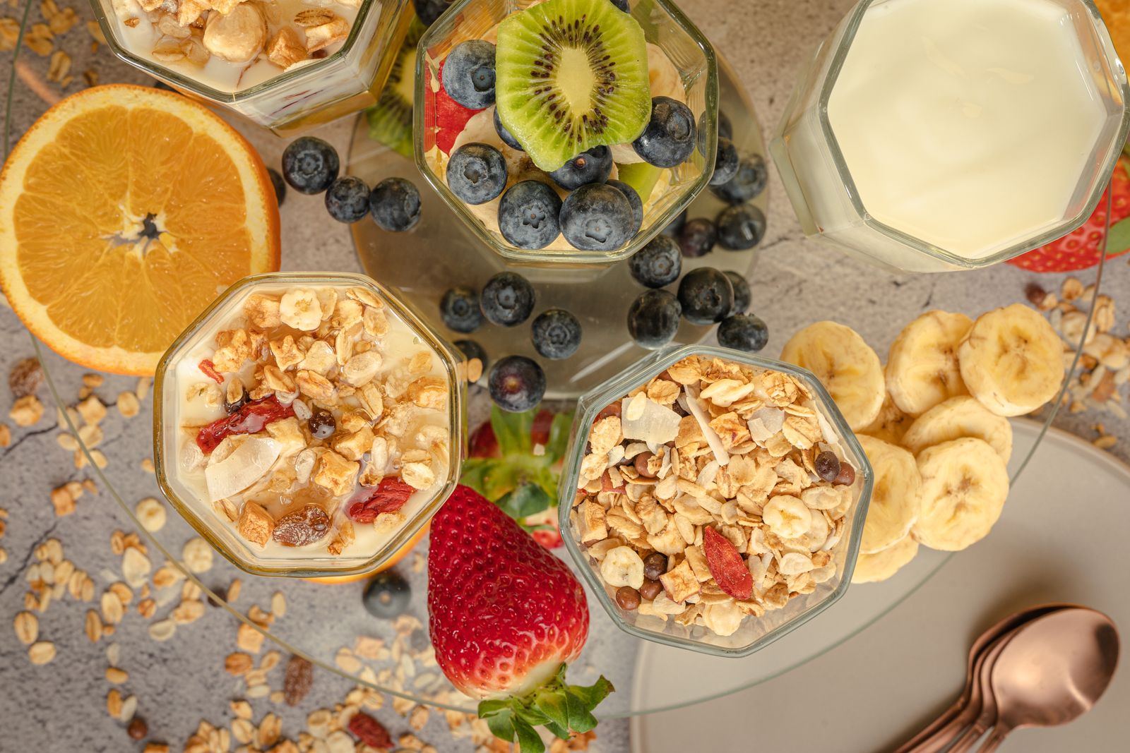 Flera glas med havre och yoghurt toppade med olika frukt: kiwi, banan, jordgubbe och blåbär