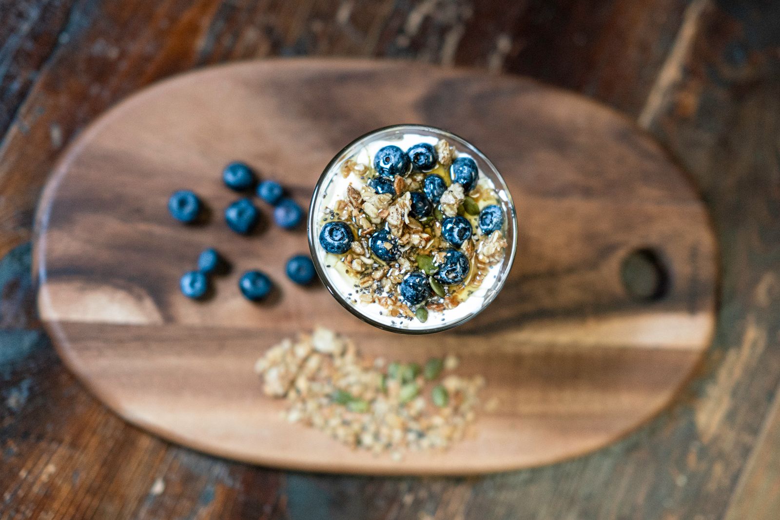 Glas med havre och yoghurt toppat med granola, blåbär och pumpafrön