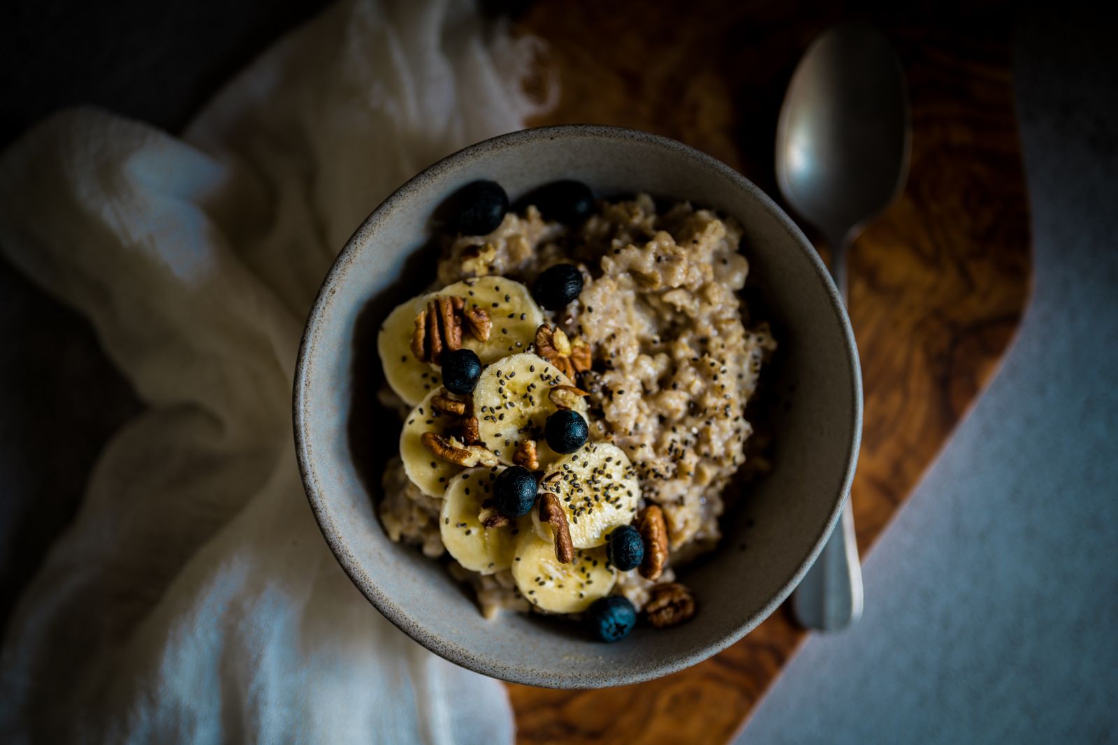 Mysig skål med havregröt toppad med banan, pekannötter, blåbär och chiafrön