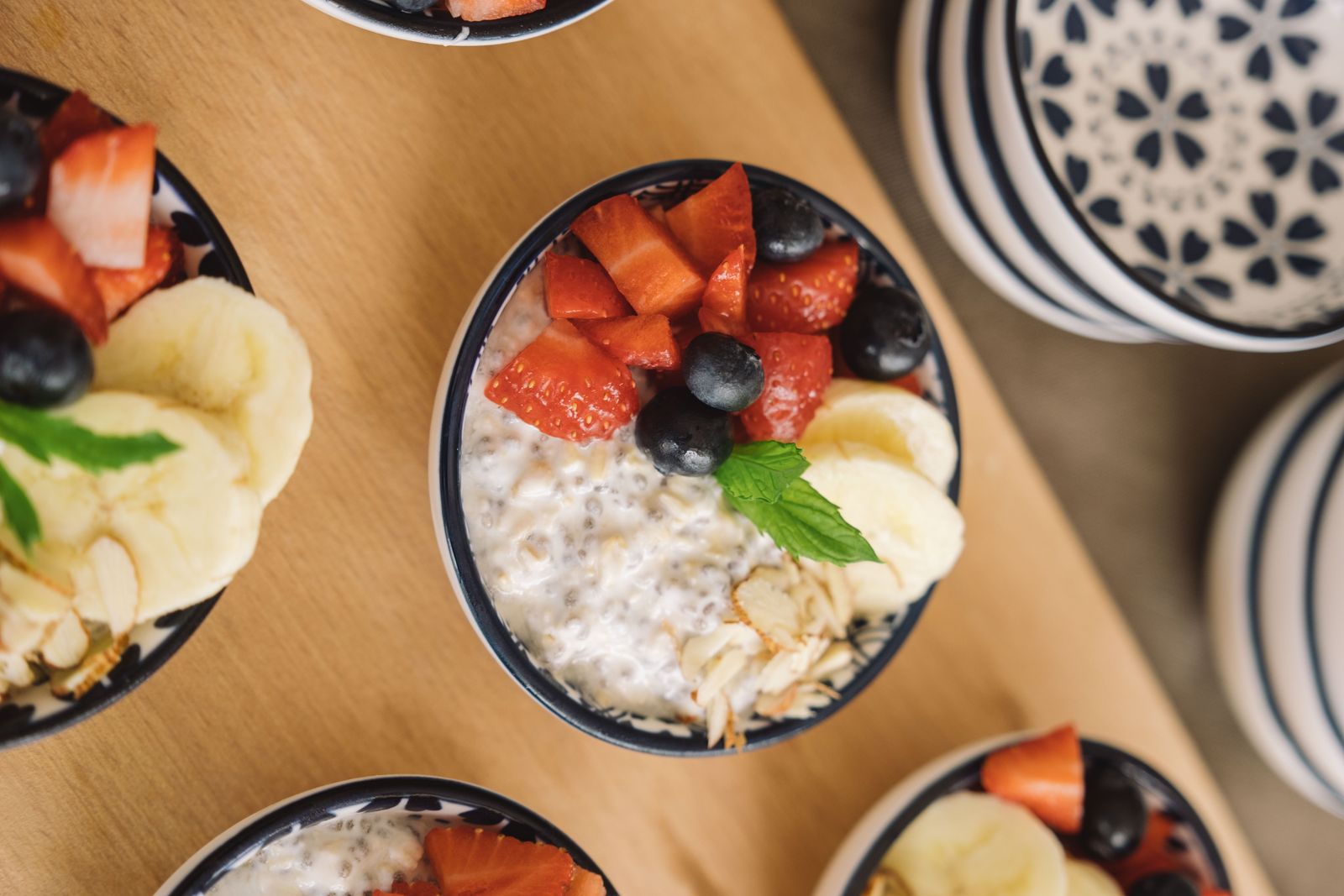 Skålar med overnight oats toppade med jordgubbar, blåbär, banan och mandel