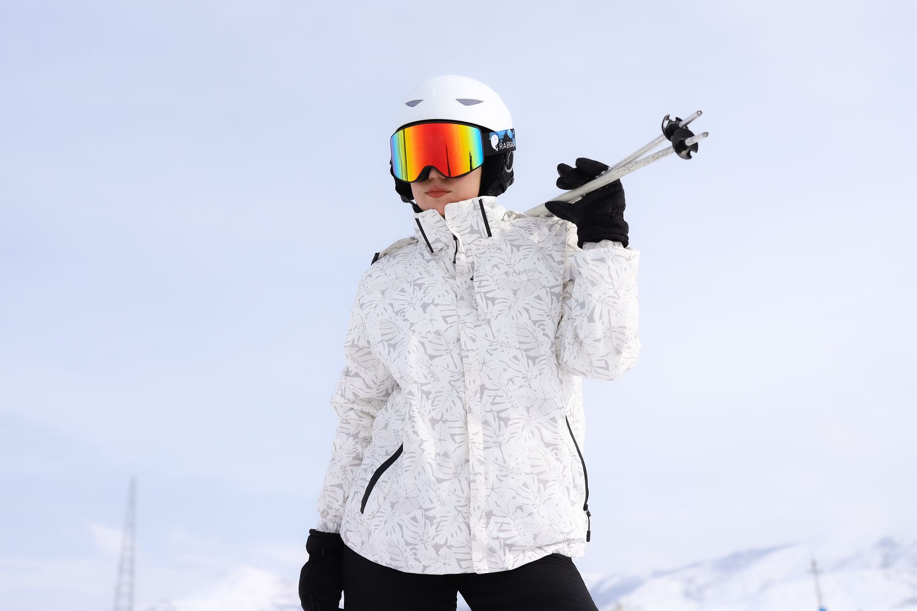 Skidåkare i vit skidjacka med hjälm och goggles på ett snötäckt berg