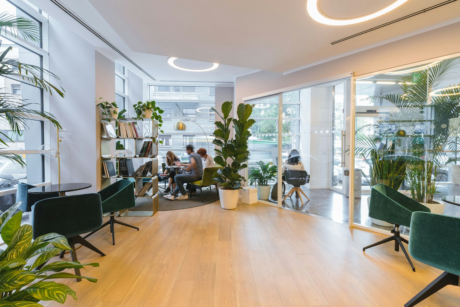 Ljust entréplan i ett coworkingkontor med gröna fåtöljer och växter