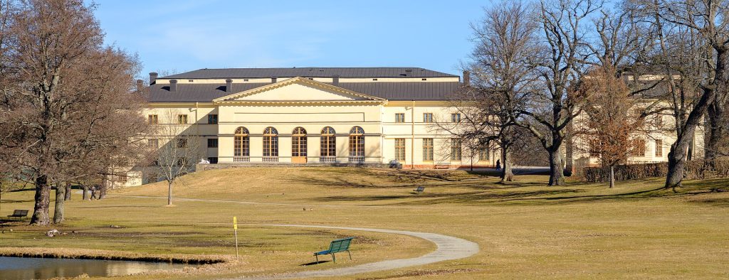 Drottningholms Slottsteater sett från slottsparken, gul huvudbyggnad med svart tak