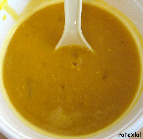 A bowl of vegan yellow pea soup with a spoon