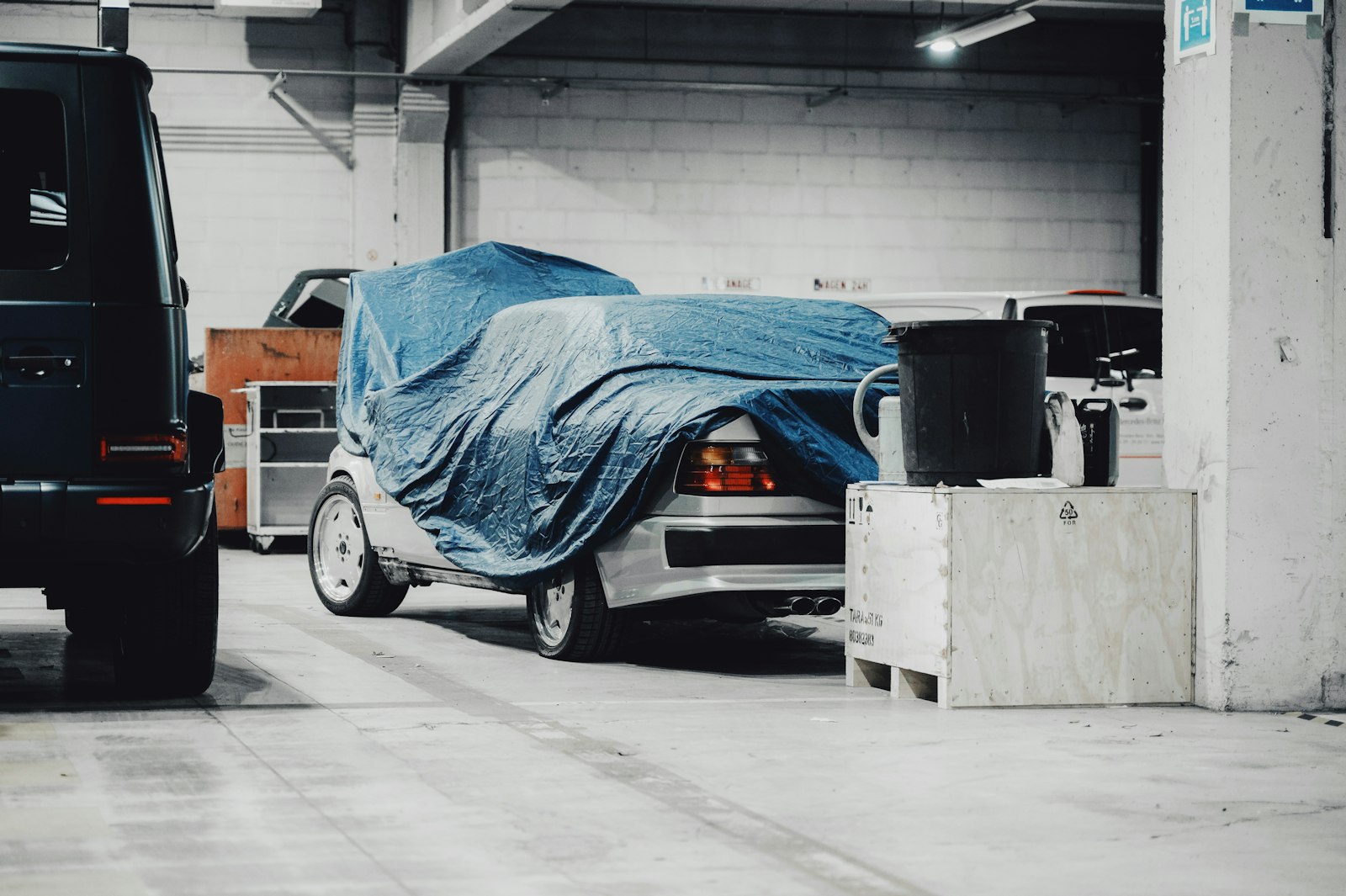 Bil under blå presenning i ett parkeringsgarage