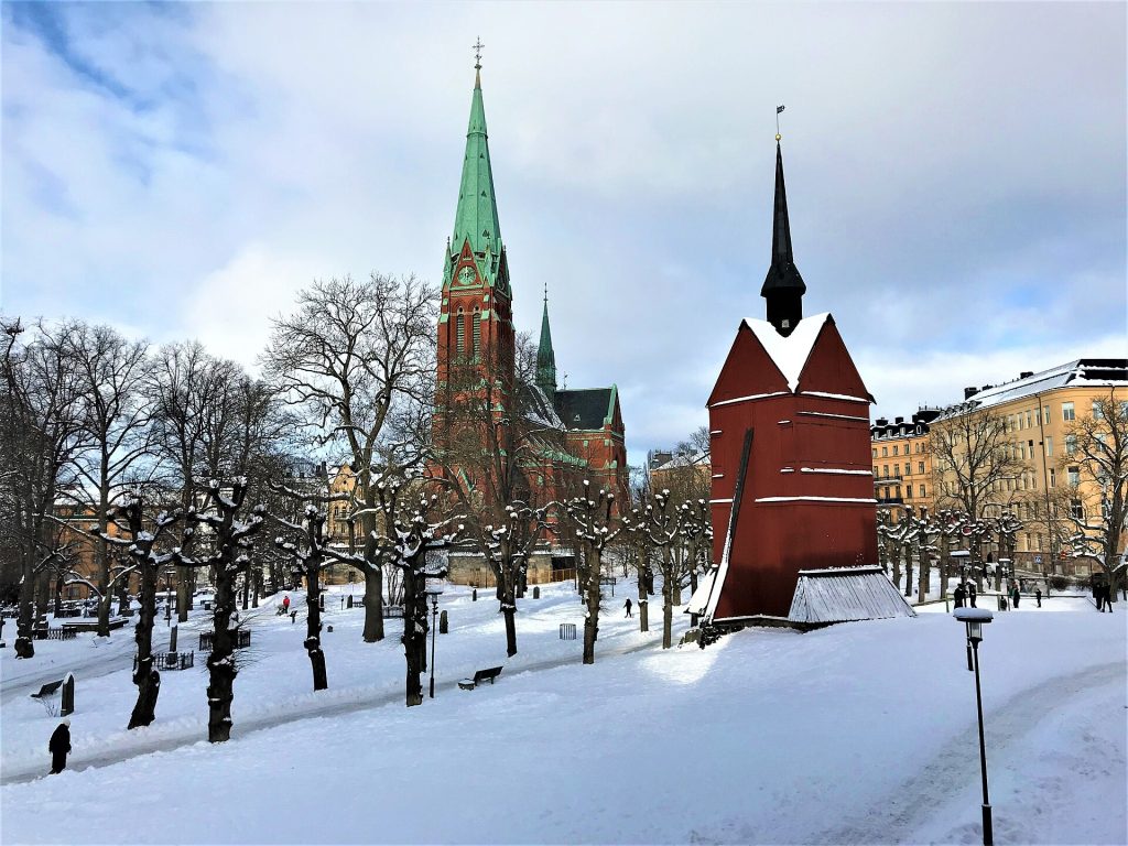 Sankt Johannes kyrka och den röda klockstapeln av trä på den snötäckta kyrkogården vid Johannes plan