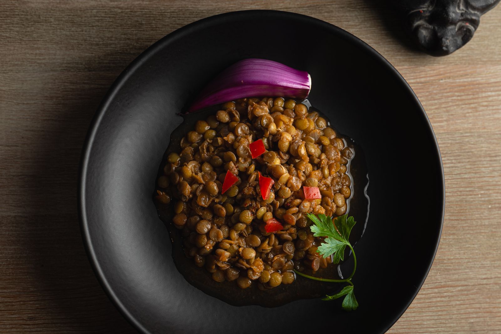 Skål med kryddig linsgryta garnerad med rödlök och paprika