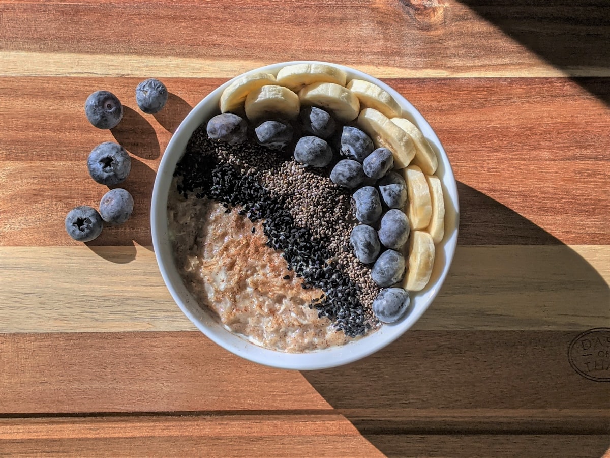 Skål med havregrynsgröt toppad med banan, blåbär och chiafrön