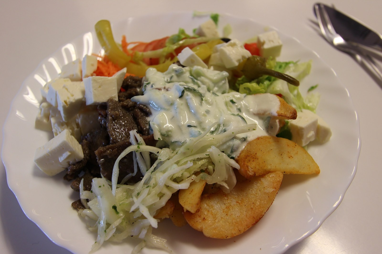 Skollunch på tallrik med kebab, klyftpotatis, tsatsiki och salladsbuffé