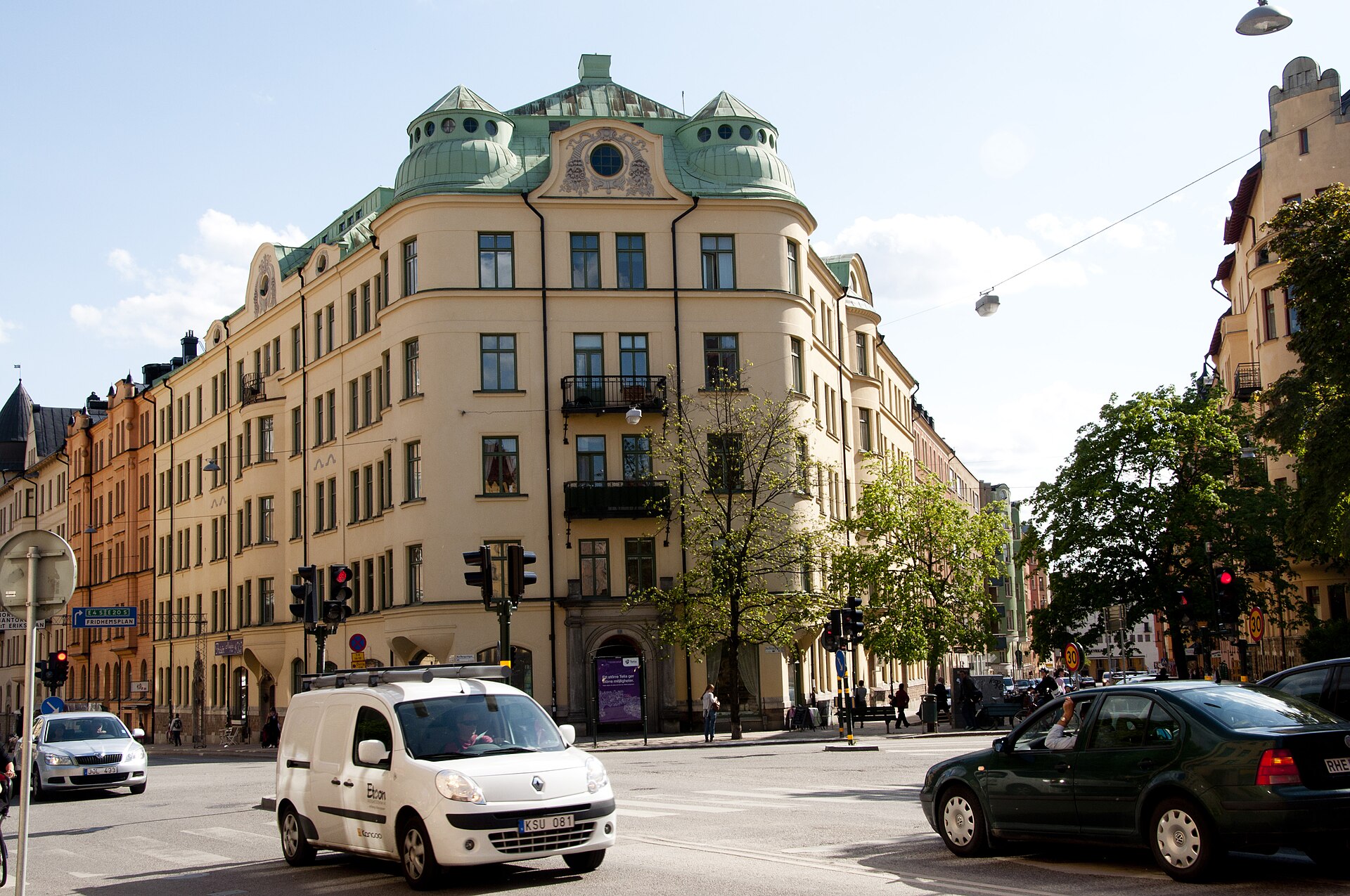 Det gula hörnhuset Formen 1 med grönt koppartak och runda takkupoler vid korsningen Karlbergsvägen, Birkagatan och Torsgatan i Birkastan.