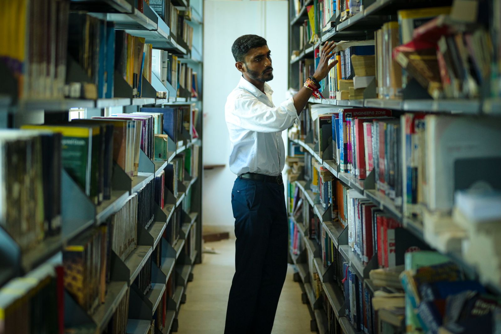 Student bläddrar bland böcker i ett universitetsbibliotek