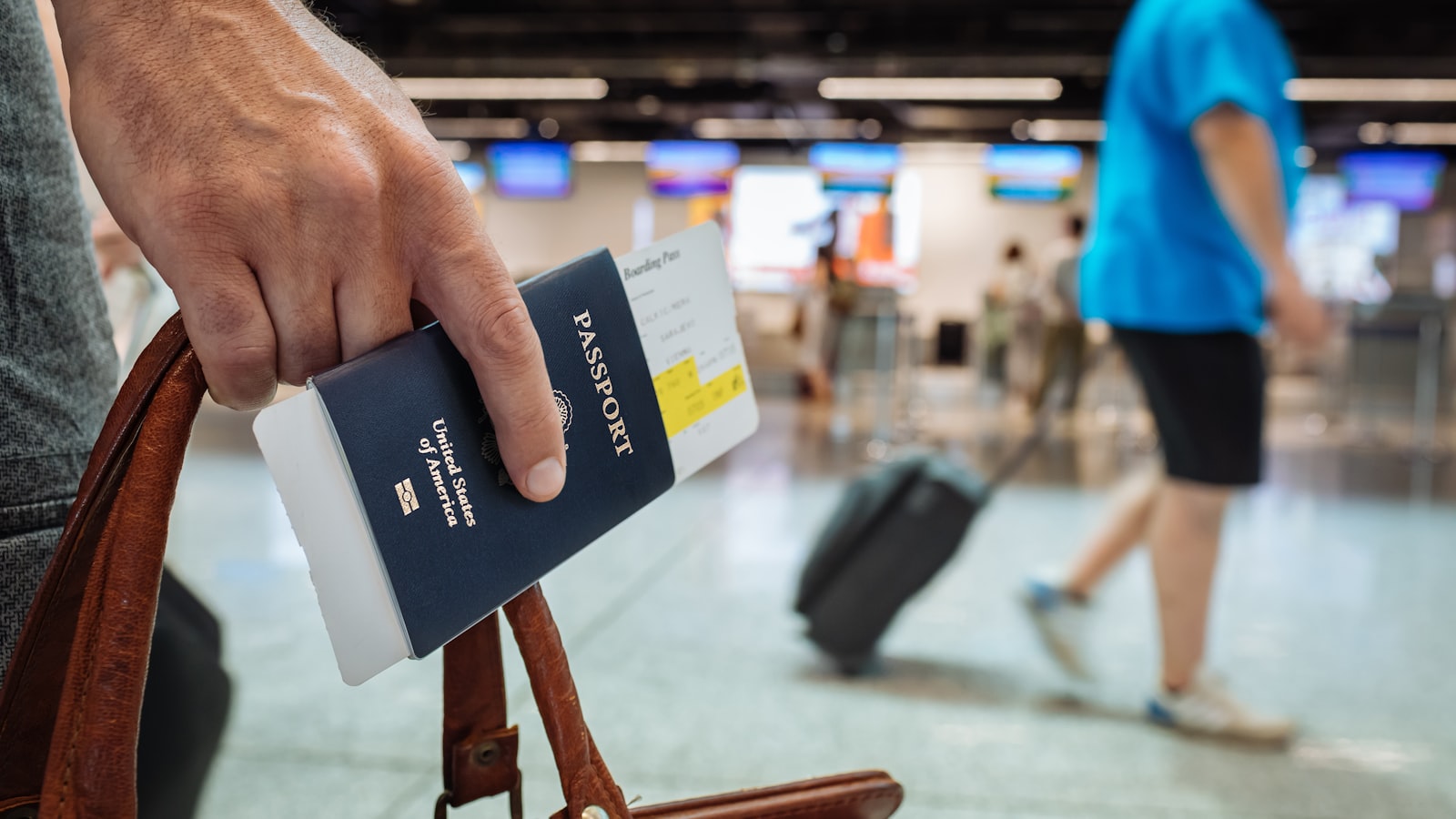 Resenär med pass och boardingkort vid en resväska på flygplatsen