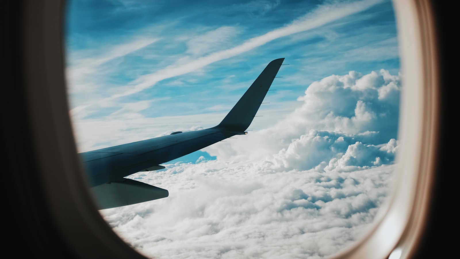 Utsikt över en flygplansvinge och moln genom kabinfönstret