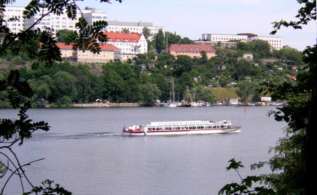 Sightseeingbåt på Årstaviken med Tantolundens kolonistugor och Södermalms hus i bakgrunden