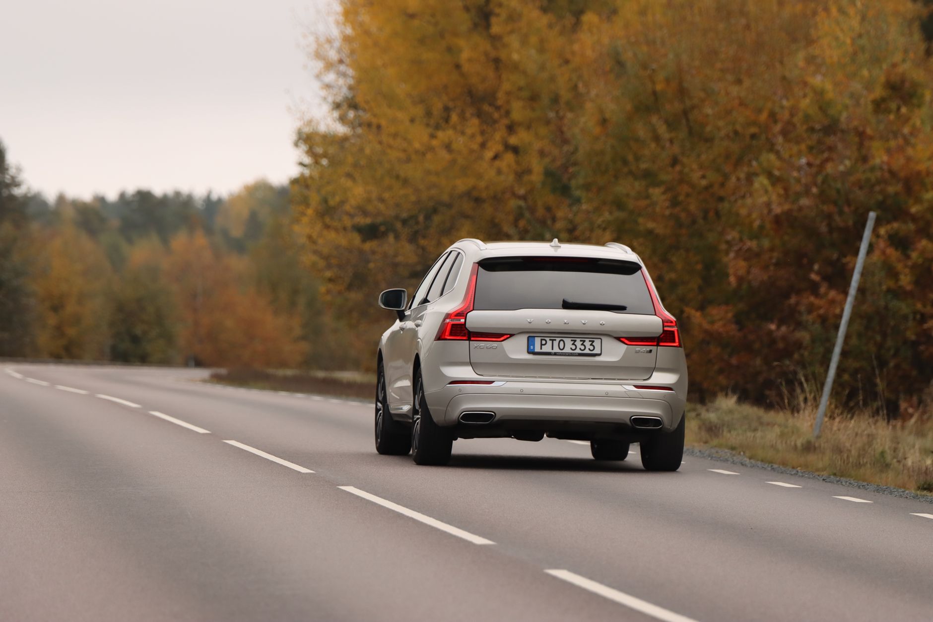 Ljus SUV bakifrån på en svensk landsväg i höstfärger
