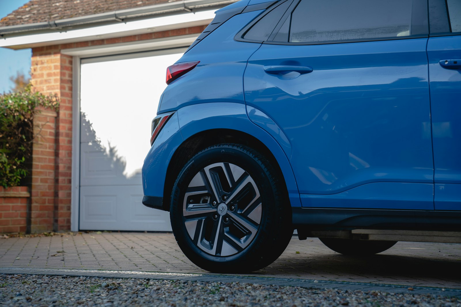 Blå bil parkerad på en uppfart framför ett garage