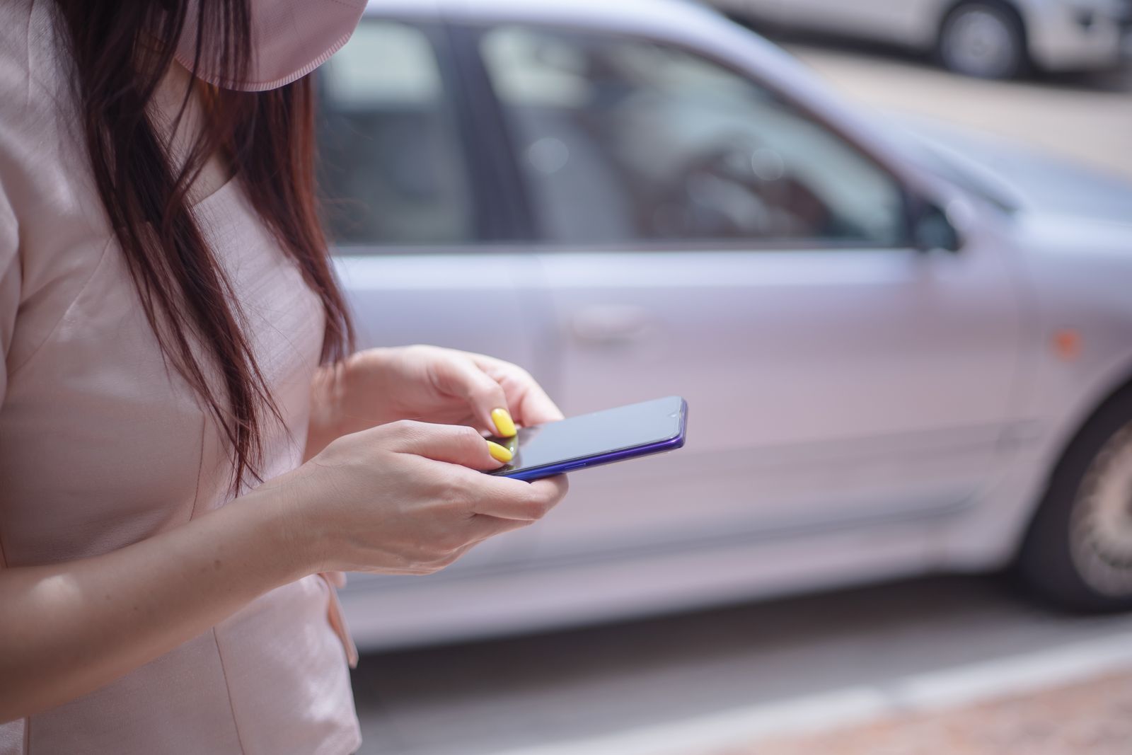 Person kontrollerar fordonsuppgifter på sin mobil framför en parkerad bil