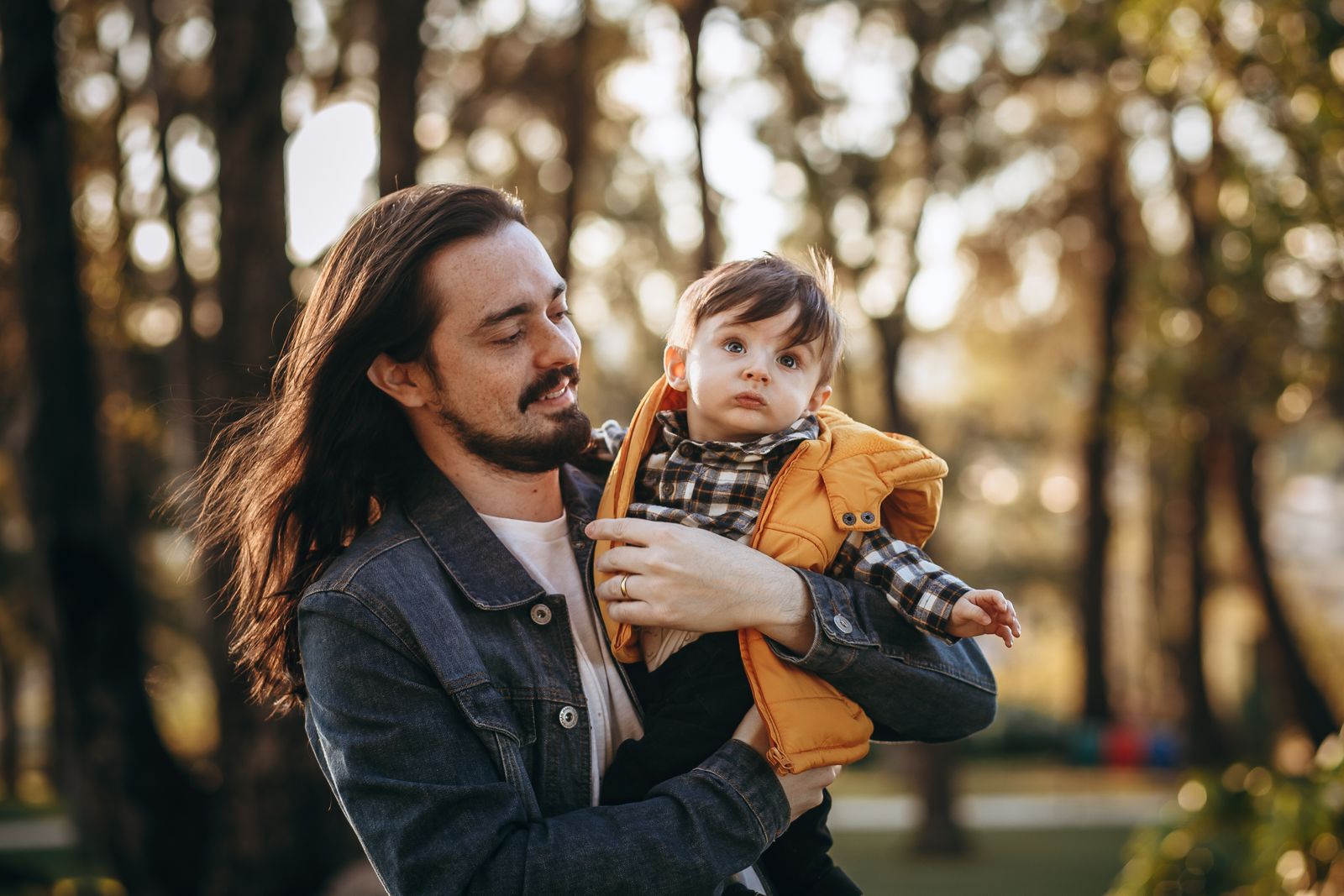 A father carrying his toddler outdoors in a forest