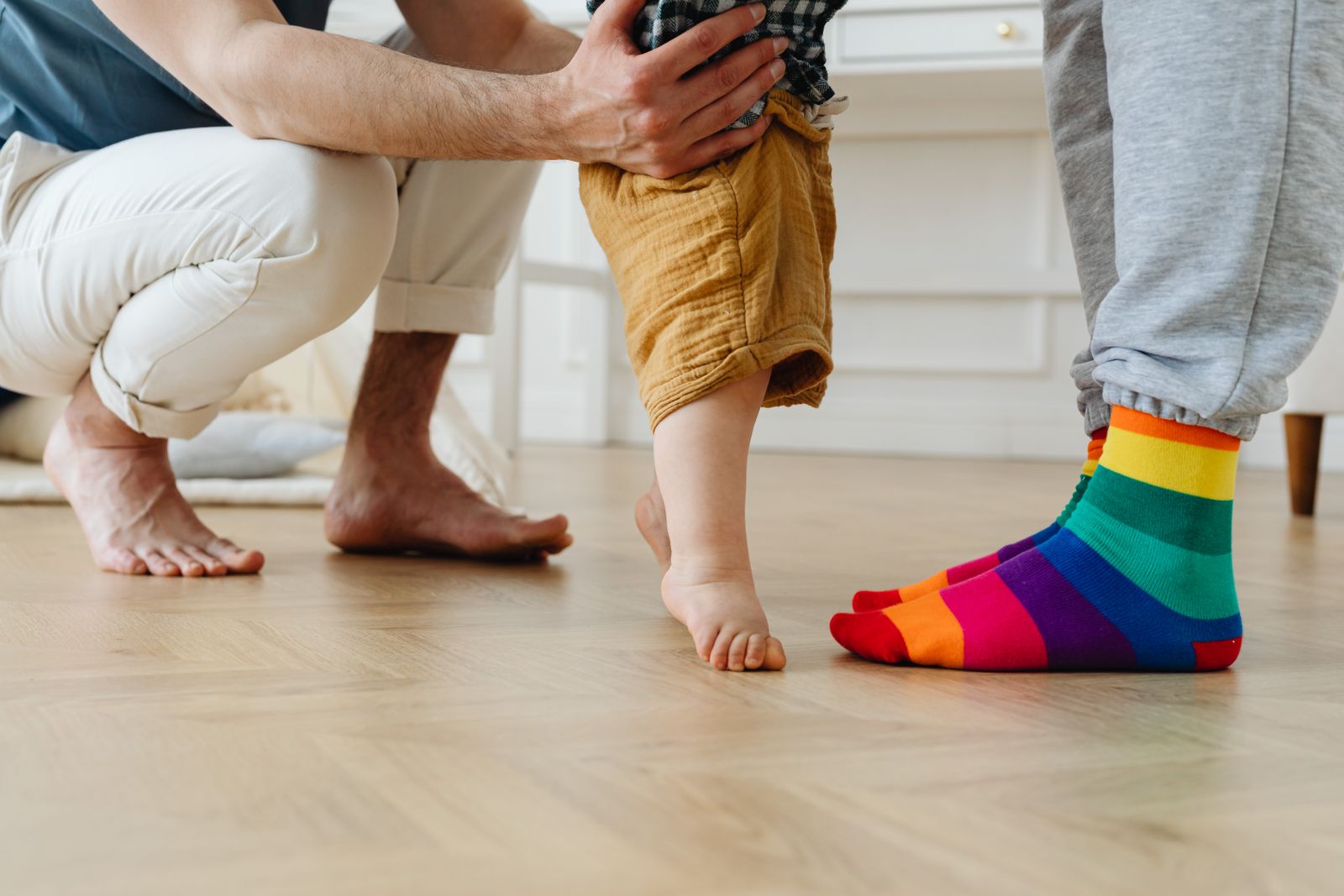 A parent helping a toddler take first steps