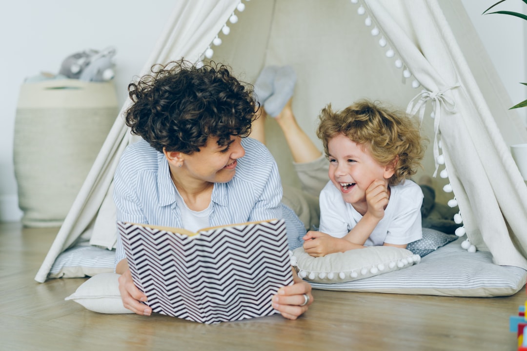 A mother and toddler laughing together while reading a book
