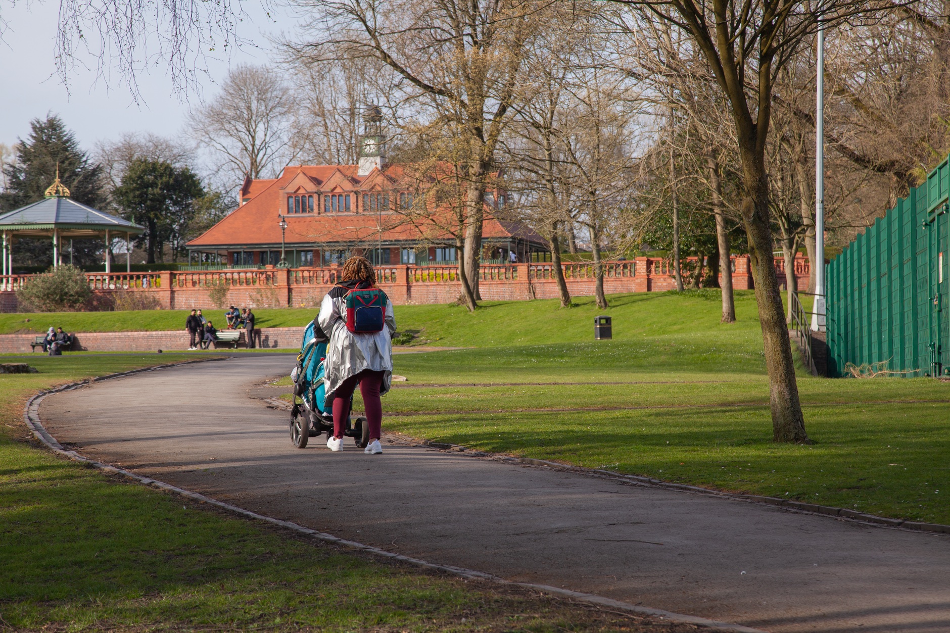 Parent pushing a pram along a park path