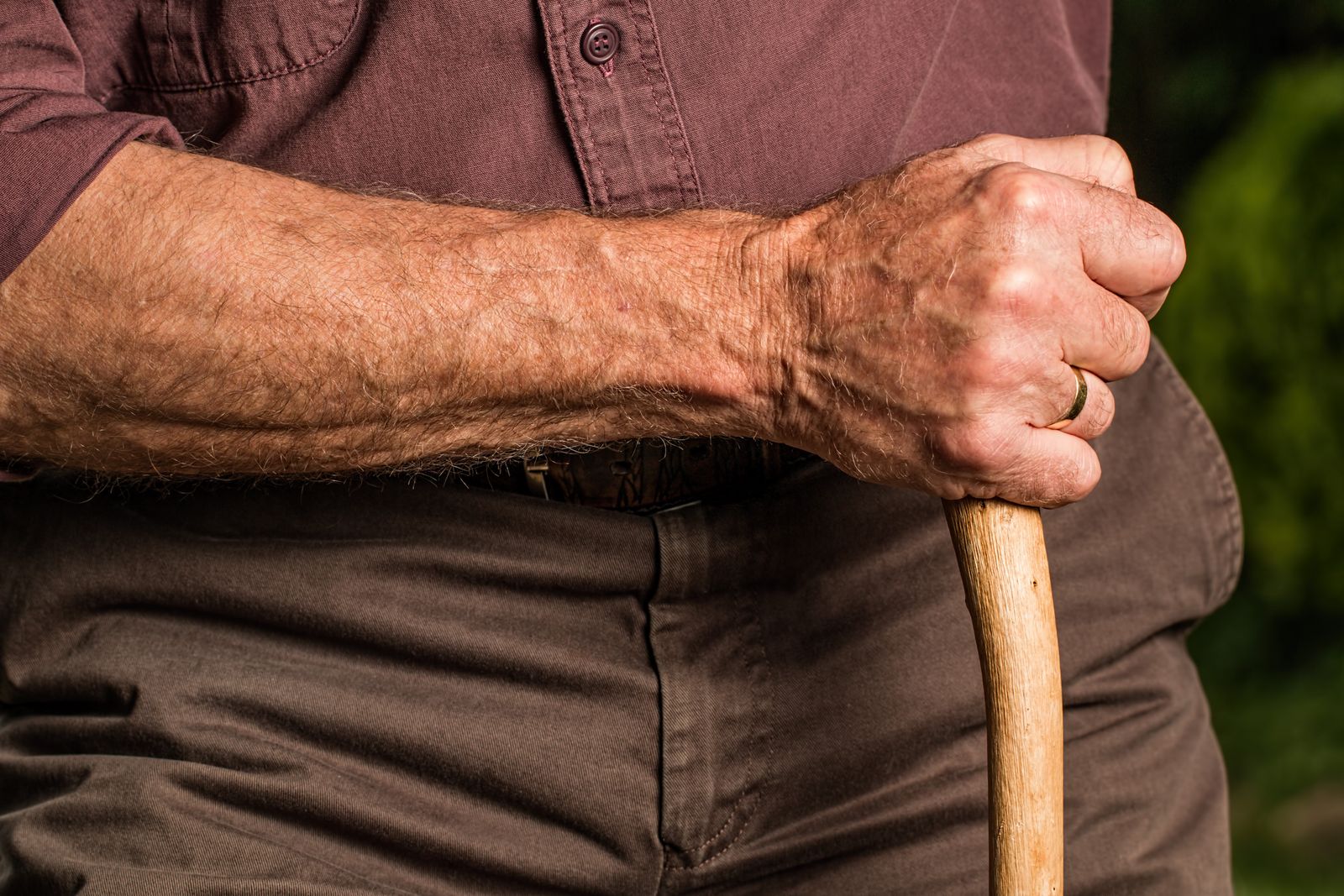 Närbild på en äldre persons hand som håller i handtaget på en käpp