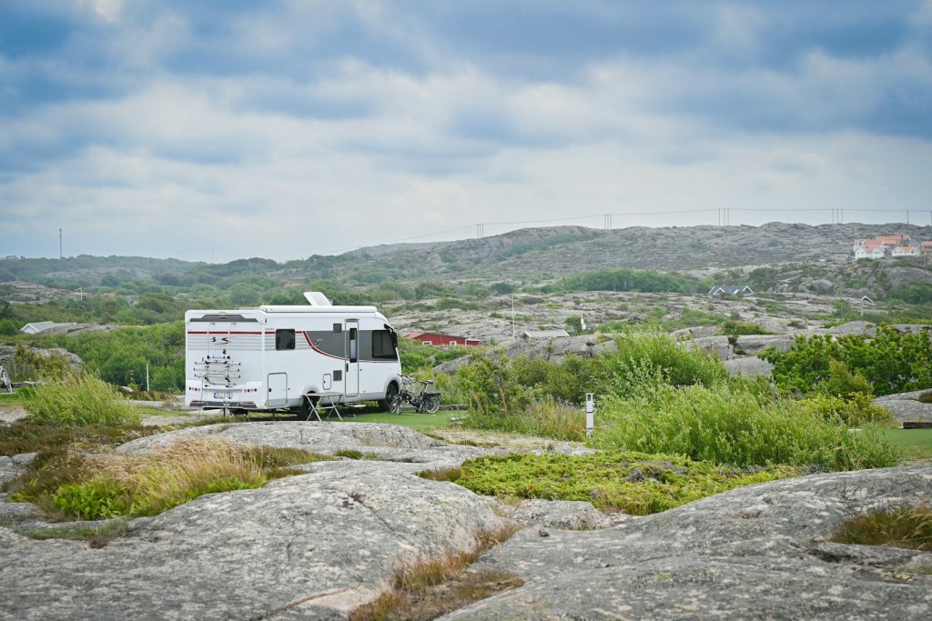 Halvintegrerad husbil parkerad bland klipphällar i ett kustlandskap