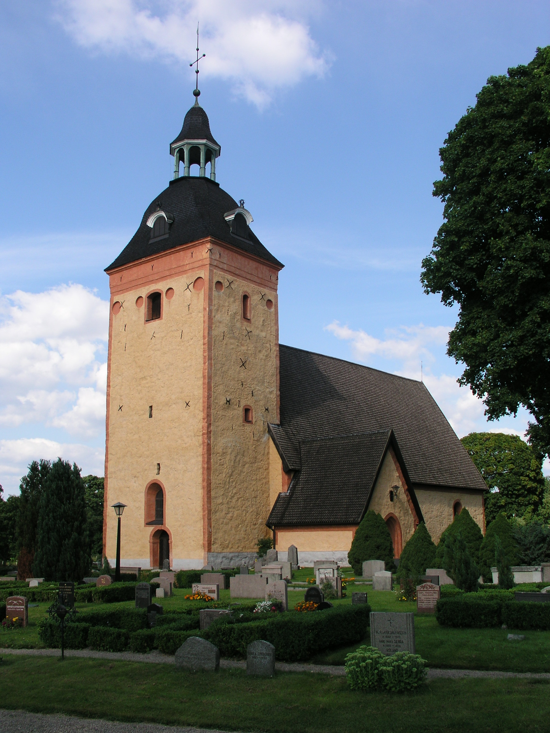Ösmo kyrka med sitt medeltida torn och kyrkogården framför